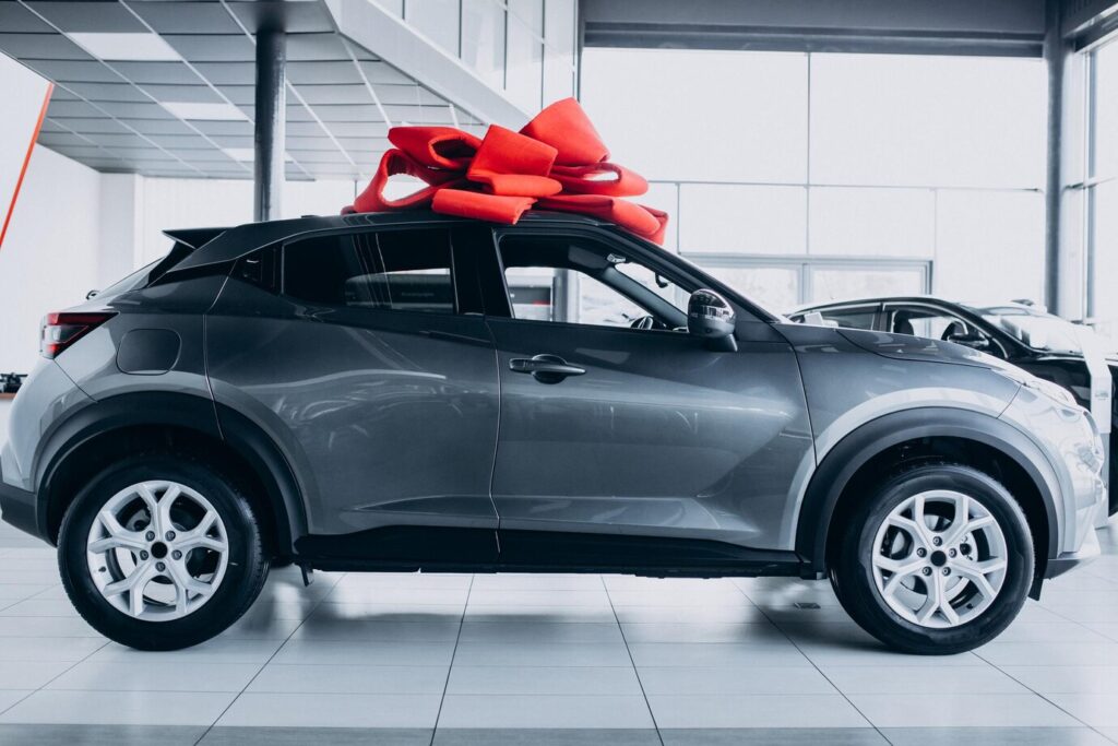 red-bow-new-car-as-present-standing-car-showroom_1303-29466-1024x683